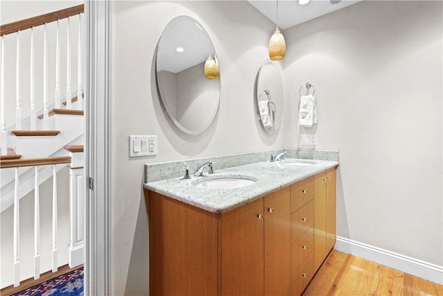 bathroom with baseboards, wood finished floors, a sink, and double vanity