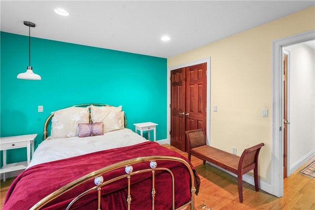 bedroom with recessed lighting, an accent wall, wood finished floors, and baseboards