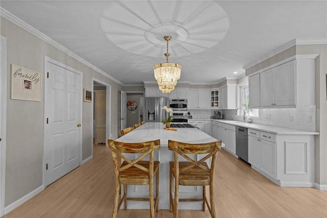 10 David Ct, East Greenwich, RI 02818 - kitchen with light wood-style flooring, glass insert cabinets, appliances with stainless steel finishes, a breakfast bar, and a chandelier