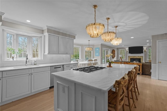 10 David Ct, East Greenwich, RI 02818 - kitchen featuring a sink, light wood-style floors, stainless steel appliances, an inviting chandelier, and a stone fireplace