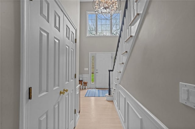 10 David Ct, East Greenwich, RI 02818 - foyer entrance featuring a wainscoted wall, light wood-type flooring, a decorative wall, a chandelier, and stairs