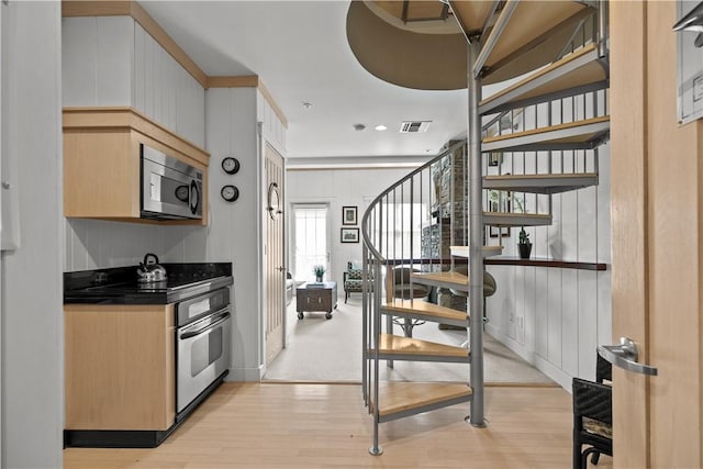 kitchen with dark countertops, appliances with stainless steel finishes, light wood-style floors, and visible vents