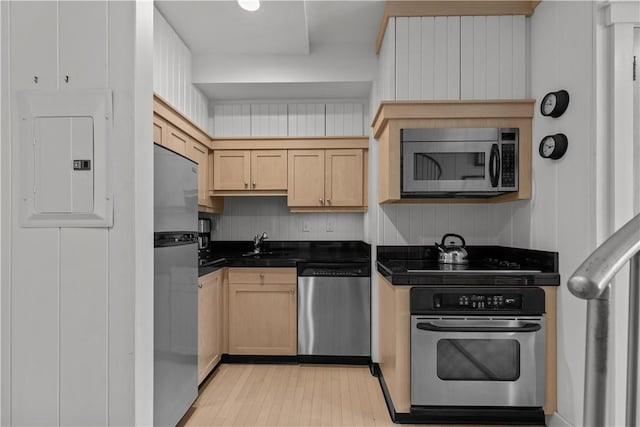 kitchen with light brown cabinets, dark countertops, a sink, electric panel, and appliances with stainless steel finishes