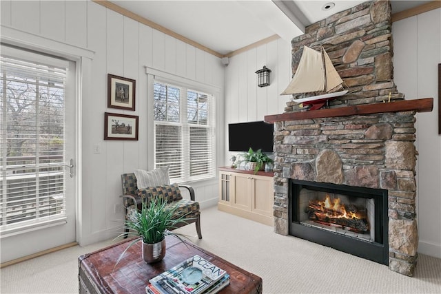 carpeted living room featuring beam ceiling and a stone fireplace