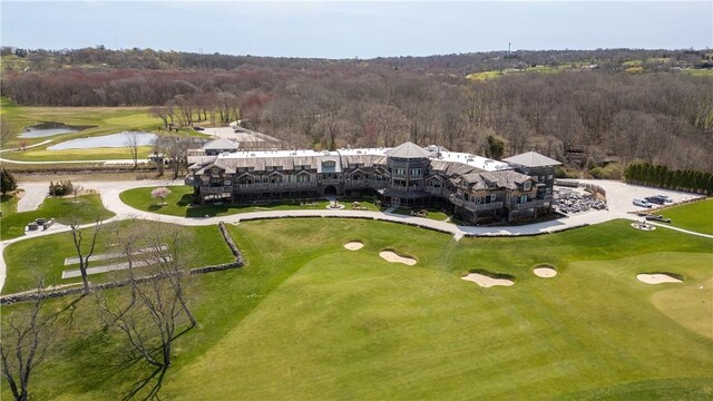 drone / aerial view with golf course view, a forest view, and a water view