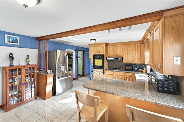 kitchen with appliances with stainless steel finishes, a peninsula, backsplash, stone counters, and under cabinet range hood