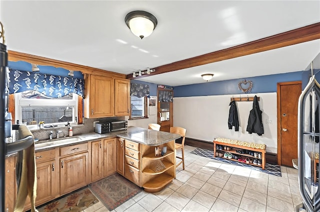 kitchen featuring open shelves, a sink, a peninsula, decorative backsplash, and light tile patterned floors
