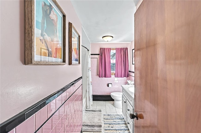 bathroom featuring tile patterned flooring, vanity, toilet, a shower with shower curtain, and tile walls