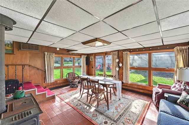 sunroom with wooden walls, a paneled ceiling, a healthy amount of sunlight, and tile patterned flooring