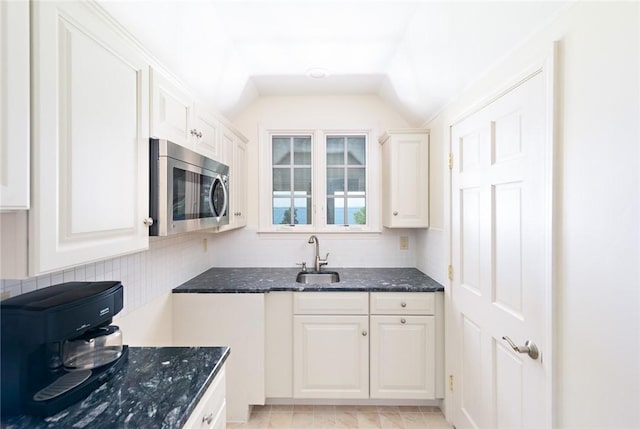 29 Reliance Dr, Bristol, RI 02809 - kitchen with white cabinets, dark stone countertops, a sink, stainless steel microwave, and decorative backsplash