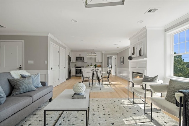 0 Greenwich Blvd Unit 203, East Greenwich, RI 02818 - living room with light wood finished floors, a glass covered fireplace, crown molding, a wainscoted wall, and a decorative wall