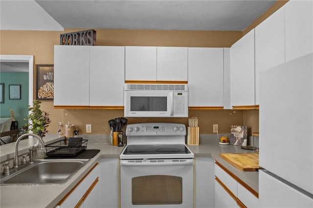 kitchen with white cabinets, a sink, white appliances, and light countertops