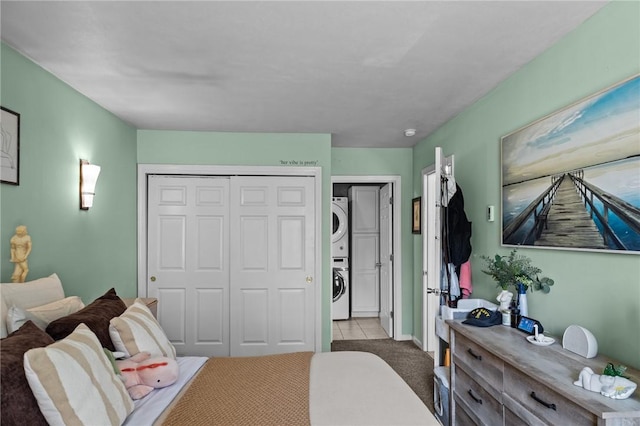 tiled bedroom with stacked washer / drying machine, carpet, and a closet