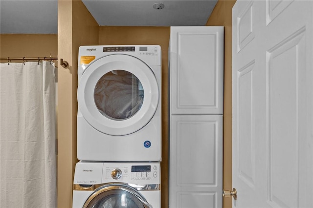clothes washing area with stacked washer and clothes dryer and laundry area