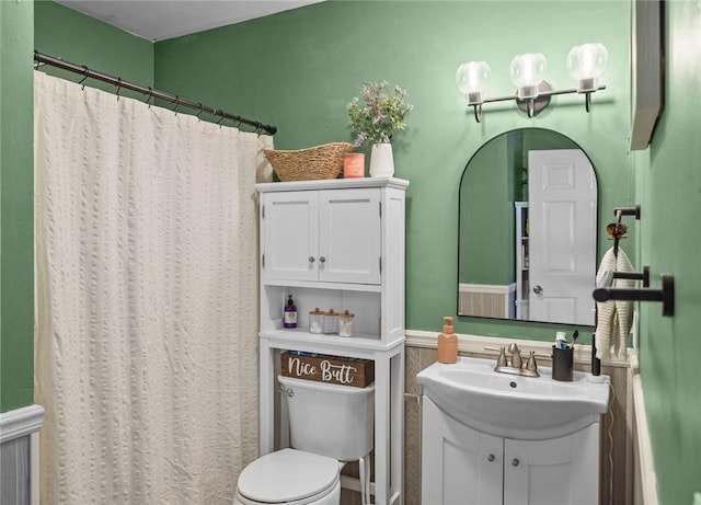 bathroom featuring a wainscoted wall, vanity, curtained shower, and toilet