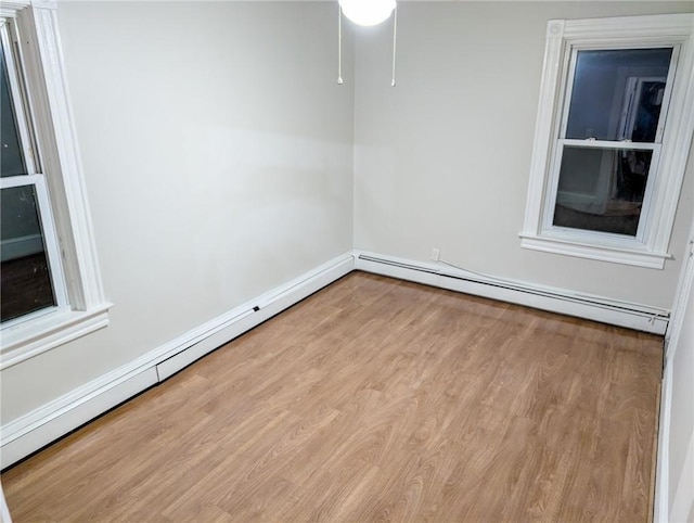 spare room with baseboard heating, a baseboard radiator, baseboards, and wood finished floors