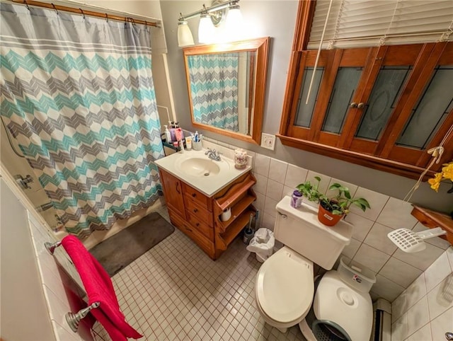 bathroom with tile patterned flooring, toilet, vanity, a shower with curtain, and tile walls