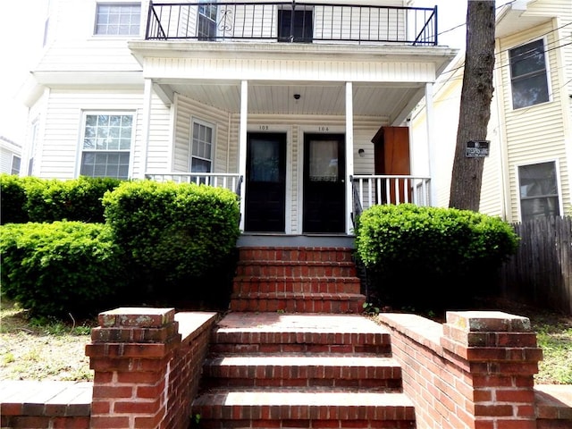 entrance to property featuring covered porch and a balcony