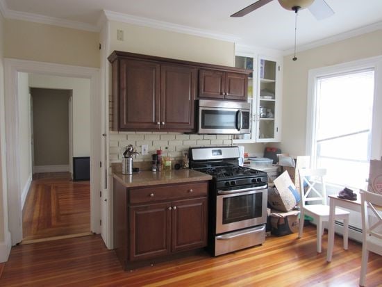 kitchen with light countertops, backsplash, a ceiling fan, ornamental molding, and appliances with stainless steel finishes