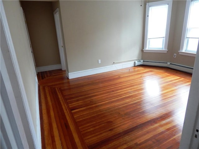 unfurnished room featuring baseboards, baseboard heating, and wood finished floors
