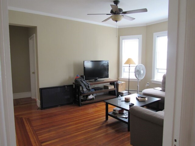 living room with dark wood-style flooring, a ceiling fan, crown molding, and plenty of natural light