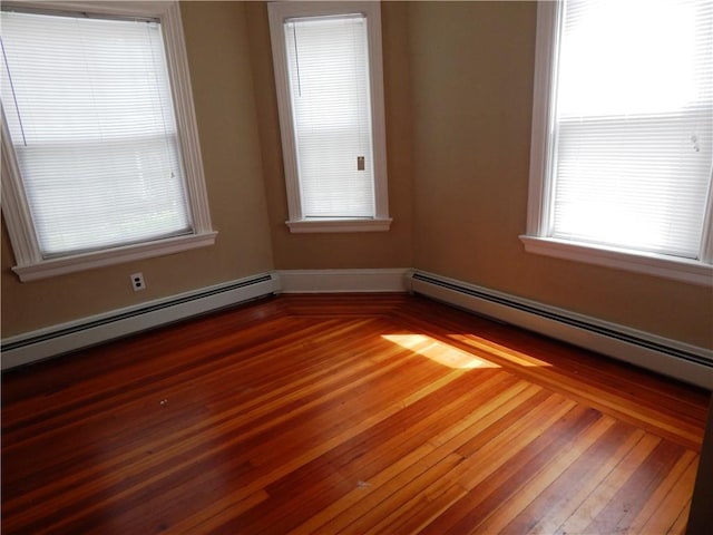 spare room featuring a baseboard heating unit and wood-type flooring
