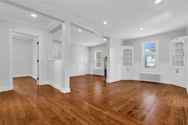 unfurnished living room featuring radiator, recessed lighting, a wainscoted wall, wood finished floors, and ornamental molding
