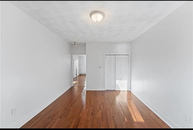 spare room featuring wood finished floors and baseboards