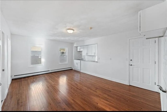 unfurnished living room with baseboard heating, baseboards, dark wood-type flooring, and a sink