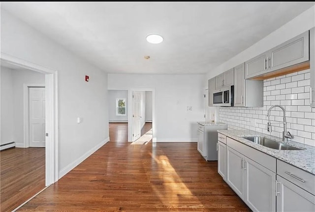 kitchen featuring stainless steel microwave, dark wood-type flooring, decorative backsplash, and a sink