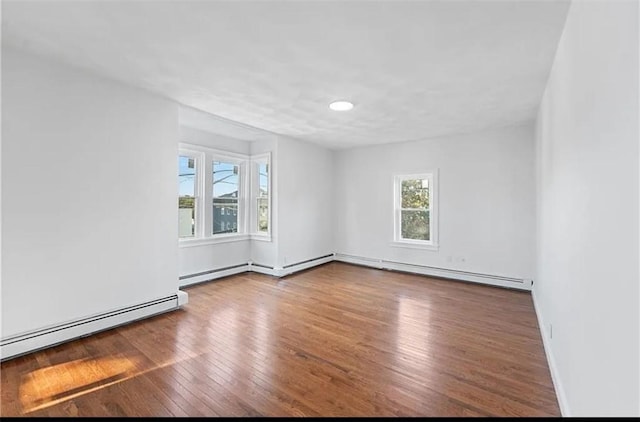 empty room featuring wood finished floors, baseboards, and baseboard heating