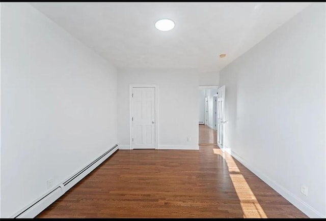 unfurnished room with baseboards, baseboard heating, and wood finished floors
