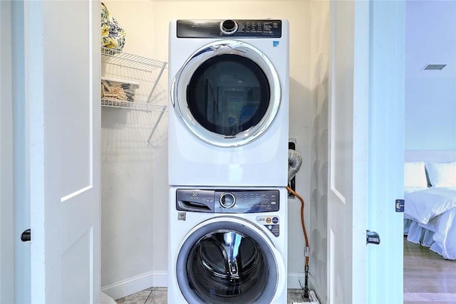 laundry room featuring laundry area, visible vents, baseboards, and stacked washer and clothes dryer