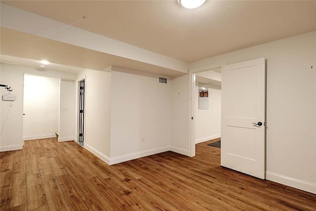 empty room with baseboards, wood finished floors, and visible vents