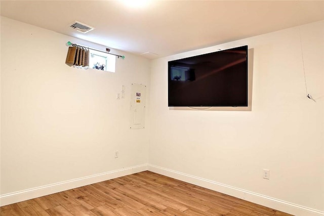 empty room with visible vents, baseboards, electric panel, and light wood-type flooring