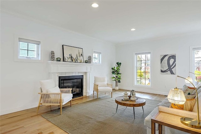living area featuring plenty of natural light, light wood-style flooring, and a tile fireplace