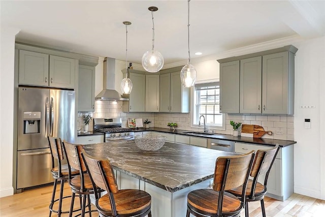 kitchen featuring light wood-style floors, wall chimney range hood, gray cabinets, a sink, and stainless steel appliances