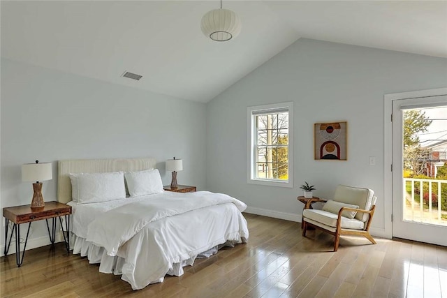 bedroom with visible vents, wood finished floors, baseboards, lofted ceiling, and access to outside