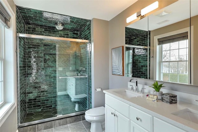 full bathroom featuring tile patterned flooring, double vanity, toilet, a shower stall, and a sink