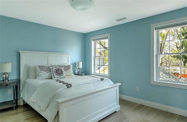 bedroom featuring light wood-type flooring, baseboards, visible vents, and multiple windows