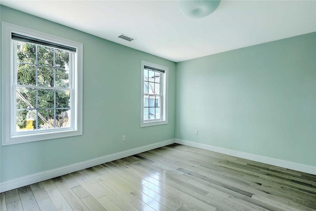empty room with baseboards, visible vents, and a wealth of natural light