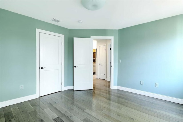 unfurnished bedroom featuring baseboards, visible vents, and wood finished floors