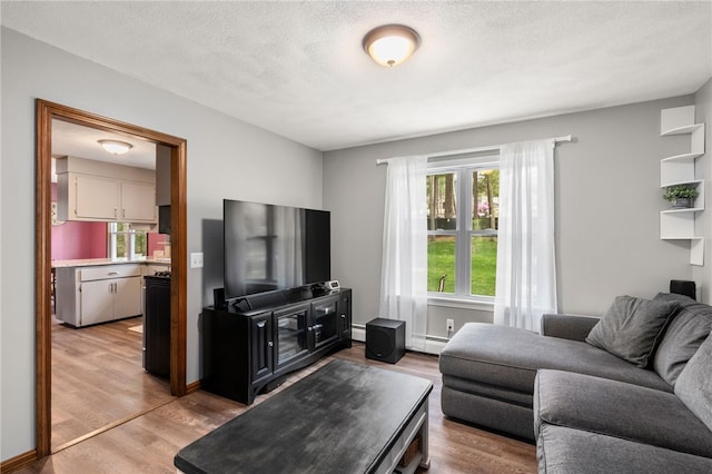 living area with a baseboard heating unit, light wood-type flooring, a textured ceiling, and baseboard heating
