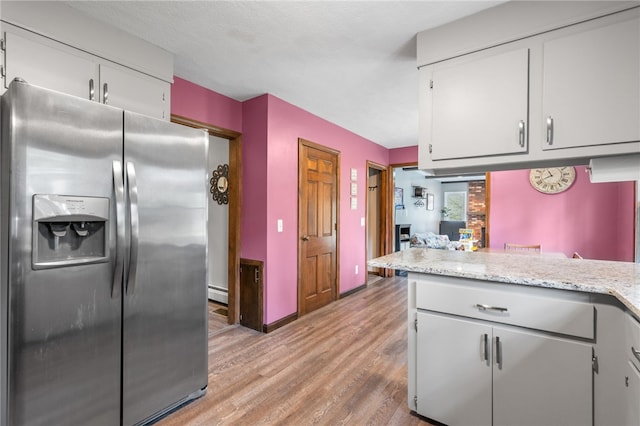 kitchen featuring light wood finished floors, baseboards, white cabinetry, baseboard heating, and stainless steel refrigerator with ice dispenser
