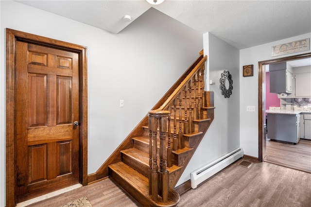 stairs with baseboards, baseboard heating, and wood finished floors