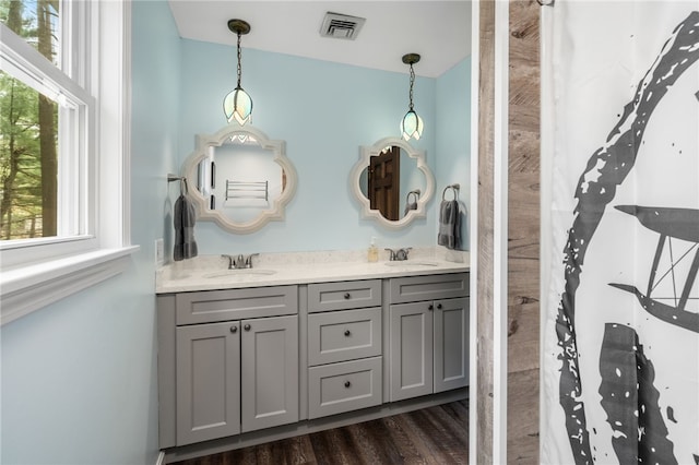 full bath with wood finished floors, a sink, visible vents, and double vanity