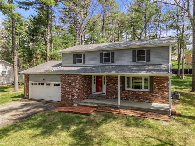 traditional-style house with a front lawn, aphalt driveway, brick siding, and a garage