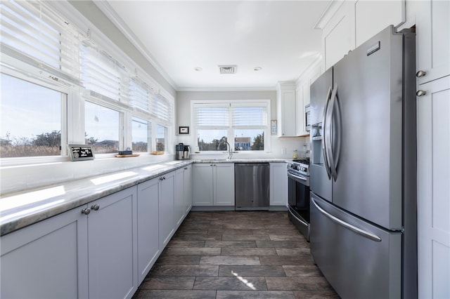 kitchen featuring white cabinets, visible vents, appliances with stainless steel finishes, light stone counters, and ornamental molding
