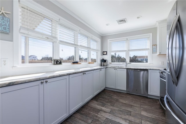 kitchen featuring light countertops, visible vents, a sink, crown molding, and appliances with stainless steel finishes