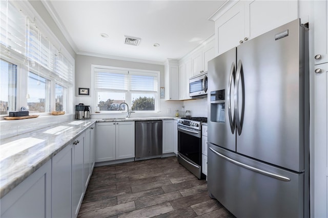 kitchen featuring visible vents, white cabinetry, light stone counters, crown molding, and appliances with stainless steel finishes